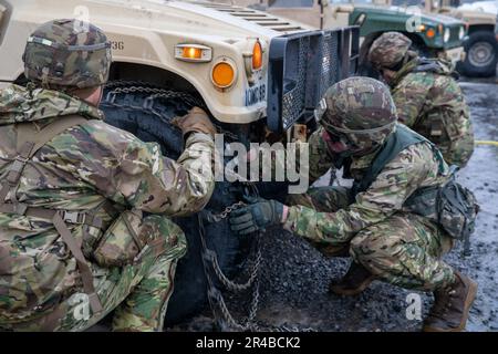 10. Bergsoldaten arbeiten zusammen, um Schneeketten auf einem HMMV in weniger als 10 Minuten zu platzieren. Die Teams konkurrieren um die schnellste Zeit, bevor sie mit der nächsten Übung fortfahren. Stockfoto