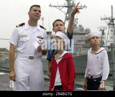 US Navy LT. Steht mit seinen Familienmitgliedern auf dem Vorfeld, bevor es zu einer eintägigen Kreuzfahrt mit Freunden und Familie an Bord der geführten Raketenzerstörerin USS Barry (DDG 52) geht. Stockfoto