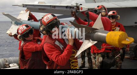 US Navy Aviation Ordnancemen, zugewiesen zum Stier des Strike Fighter Squadron Three Seven (VFA-37), laden ein CATM-9 herunter. Stockfoto