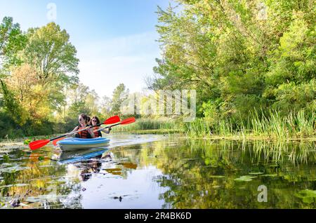 Kajaktour mit der Familie, Paddeln mit Mutter und Kind auf einer Kanutour auf dem Fluss, aktives Sommerwochenende und Urlaub, Sport- und Fitnesskonzept Stockfoto