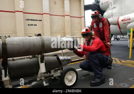US Navy Aviation Ordnancemen platzieren GBU-38 500-Pfund-Satelliten-Bomben in einem Kampfaufzug. Stockfoto
