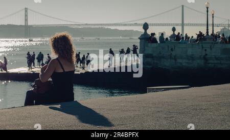 Eine Gruppe von Menschen, die den atemberaubenden Sonnenuntergang vom Ende eines Piers auf dem Tejo in Lissabon bewundern Stockfoto