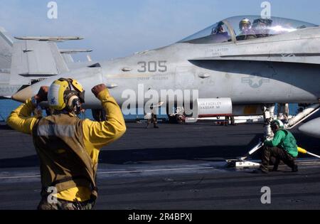 US Navy Aviation Boatswain's Mate 3. Class leitet den Piloten einer F-A-18C Hornet bei der Vorbereitung auf den Start. Stockfoto