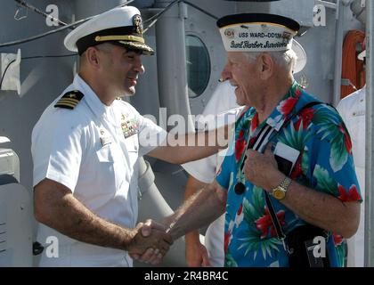 US Navy Veterans des Zerstörers der Wickes-Klasse USS ward (DD 139) aus der Zeit des Zweiten Weltkriegs werden an Bord der geführten Raketenfregatte USS Crommelin (FFG 37) vom kommandierenden Offizier des Schiffes begrüßt. Stockfoto