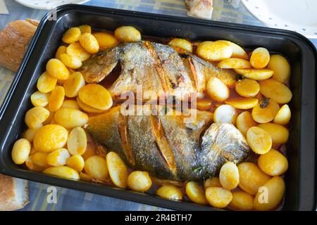 Köstlicher gerösteter Seebrassen-Fisch mit Kartoffeln und Sauce auf dem Tisch Stockfoto