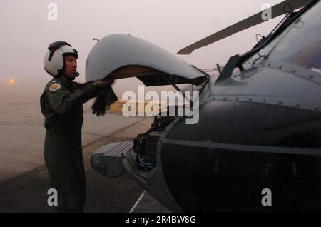 US Navy LT. Ein MH-60s Seahawk-Hubschrauberpilot, der den Black Jacks des Helicopter Sea Combat Squadron Two One (HSC-21) zugeteilt wurde, führt eine Vorflugüberprüfung durch. Stockfoto