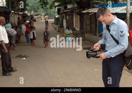 US Navy-Journalistin 2. Klasse, die dem American Forces Network zugeteilt ist, Sigonella, Sizilien, filmt Video von den Menschen in Monrovia. Stockfoto