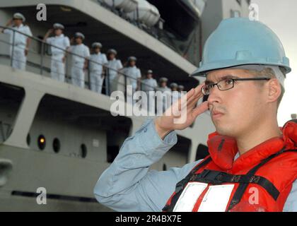 US Navy Sonar Technician 3. Class salutiert dem National Fähnrich in den Morgenfarben, bevor er das peruanische Transportschiff BAP Mollendo (ATC 131) abwirft. Stockfoto