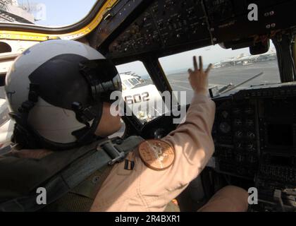 US Navy Ein Pilot, der dem Flottenlogistik-Support-Geschwader Four Zero (VRC-40) zugewiesen ist, signalisiert dem Flugzeugkapitän. Stockfoto