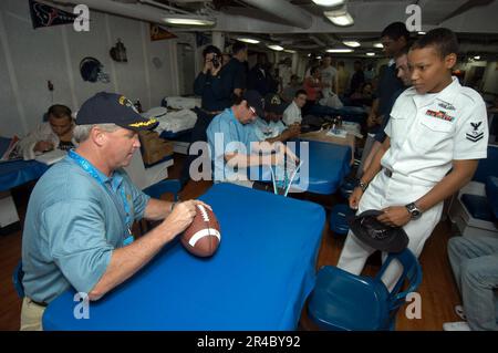 DER Linebacker der US Navy National Football League (NFL) Atlanta Falcons, Keith Brookings, Center, und der Cheftrainer der Carolina Panthers, John Fox, links, signieren Seglern Autogramme. Stockfoto