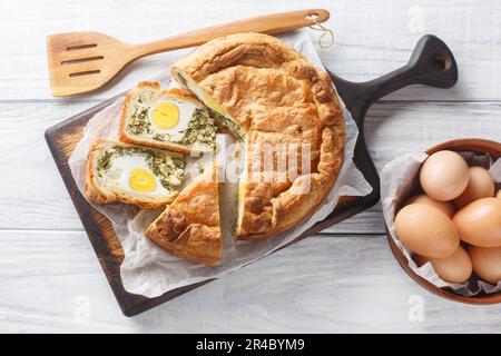 Torta Pasqualina ist eine traditionelle italienische Osterspezialität aus Blätterteig, Ricotta-Käse, Spinat und Eiern auf dem Holzbrett Stockfoto