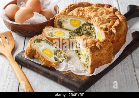 Torta Pasqualina ist eine traditionelle italienische Osterspezialität aus Blätterteig, Ricotta-Käse, Spinat und Eiern auf dem Holzbrett Stockfoto