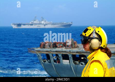 US Navy Landing Signal Enlisted (LSE), Gunner's Mate 3. Class bereitet sich auf den nächsten Helikopter vor, der an Bord des Landungsschiffes USS Harpers Ferry (LSD 49) das Flugdeck erreicht. Stockfoto