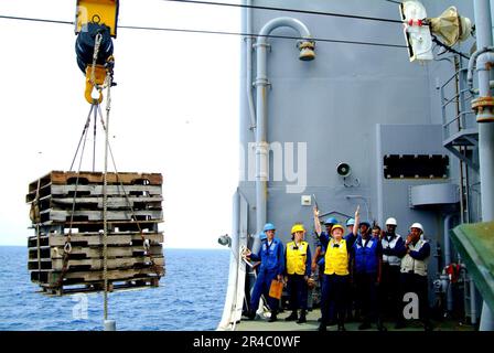 US Navy-Matrosen geben Handzeichen, um Paletten vom militärischen Sealift-Kommando (MSC) in die Wiederauffüllungsanlage USNS Yukon (T-AO 202) zu transportieren. Stockfoto