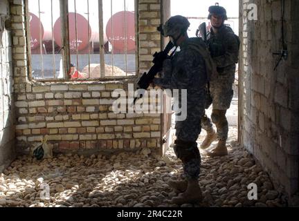 US Navy zwei USA Soldaten des 66. Rüstungsregiments, Alpha Company, durchsuchen ein verlassenes Gebäude, um sicherzugehen, bevor sie Geschäfte mit Einwohnern in der Nähe machen. Stockfoto