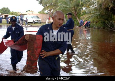 US Navy Petty Officers, die dem geführten Raketenkreuzer USS Lake Erie (CG 70) zugeteilt sind, tragen einen Auslassschlauch während einer Deflugoperation auf der überschwemmten hawaiianischen Insel. Stockfoto