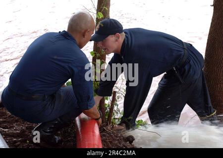 US Navy Petty Officers, die dem Guided-Raketenkreuzer USS Lake Erie (CG 70) zugeteilt sind, bemannten während einer Deflugoperation einen Auslassschlauch. Stockfoto