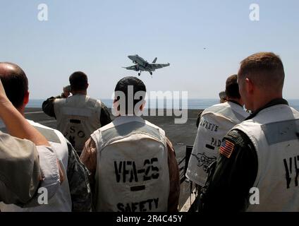 US Navy Landing Signal Officers (LSOs) beobachten eine F-A-18C Hornet, während sie sich an Bord des Flugzeugträgers USS Ronald Reagan der Nimitz-Klasse (CVN 76) dem Cockpit nähert. Stockfoto