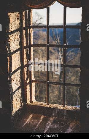 Ein wunderschönes Steinfenster mit eisernen Gittern, beleuchtet von der Sonne an einem sonnigen Tag Stockfoto