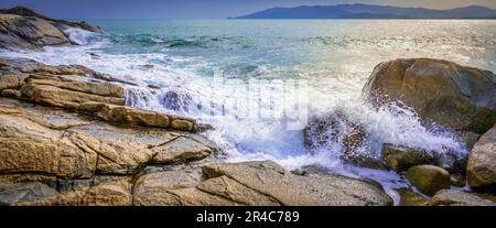 Eine riesige Fläche aus blauem Wasser erstreckt sich so weit das Auge reicht, mit großen felsigen Felsvorsprüngen, die eine malerische natürliche Grenze bilden Stockfoto