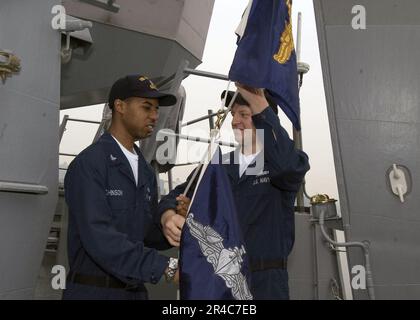 US Navy Quartermaster 3. Class Left und Quartermaster 2. Class Right, erhebe den gelisteten Surface Warfare Specialist (ESWS) Pennant. Stockfoto