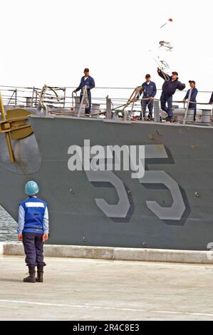 US Navy Ein Besatzungsmitglied an Bord des geführten Raketenzerstörers USS Stout (DDG 55) wirft bei der Ankunft an der Naval Station Norfolk, VA, eine Anlegestelle aus Stockfoto