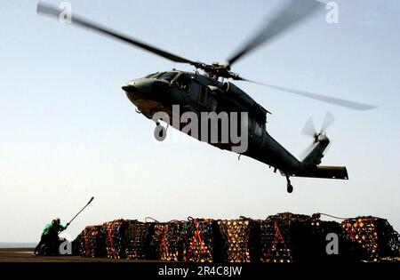 US Navy-Matrosen, die dem Flugzeugträger USS Ronald Reagan (CVN 76) der Nimitz-Klasse zugeteilt sind, bereiten sich darauf vor, Fracht an einem MH-60s Knighthawk zu befestigen. Stockfoto