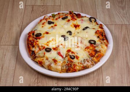 Hähnchen-Barbecue-Pizza auf einem Teller mit Holzhintergrund. Stockfoto