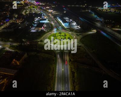 Luftaufnahme einer belebten Straße und Autobahnkreuzung, die bei Nacht von hellen Lichtern beleuchtet werden Stockfoto