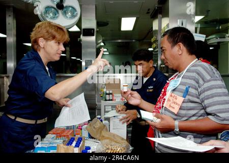 US Navy Chief Hospital Corpsman erklärt einem Patienten die richtige Medikamentendosierung während eines medizinischen und zahnärztlichen Zivilaktionsprojekts. Stockfoto