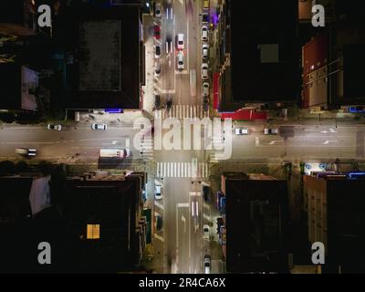 Eine abendliche urbane Straßenszene mit einer Vielzahl von Fahrzeugen, die an einer belebten Kreuzung fahren Stockfoto