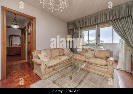 Cremefarbene Stoffsofas mit Teppich und Erkerfenster mit Fenstern und Vorhängen Stockfoto