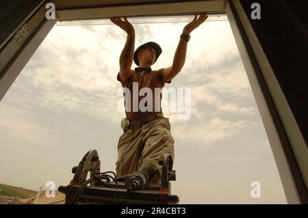 US Navy Construction Elektriker der Klasse 2. des Naval Mobile Construction Battalion Seven (NMCB-7) installiert im Rahmen des Baus eines Schlafzimmers in Dikhil eine Flutlampe. Stockfoto