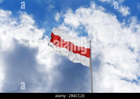 Flagge der Proteste in Belarus 2020. Die weiß-rot-weiße historische Flagge der Republik Belarus winkt vor blauem Himmel und Wolken. Stockfoto