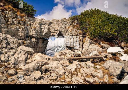 Felsbogen in den österreichischen Alpen. Blick über die Berge vom Felsfenster im Loser Peak, Tote Berge (Totes Gebirge) in den österreichischen Alpen. Stockfoto