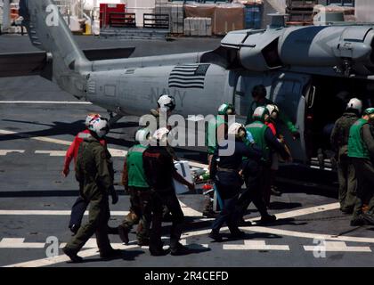 US Navy Seeleute tragen einen Patienten zu einem wartenden MH-60s Helikopter an Bord des Krankenhausschiffs USNS Mercy (T-AH 19) des militärischen Sealift-Kommandos. Stockfoto