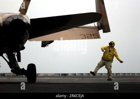 US Navy Chief Aviation Boatswain's Mate leitet den Piloten einer F-A-18 Hornet, die den Rough Jaiders des Strike Fighter Squadron One Two Five (VFA-125) an Bord der Nimitz-Klasse Aircr zugeteilt wurde. Stockfoto