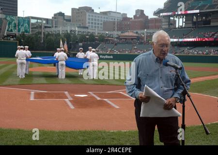 US Navy Major League Baseball Hall of Fame Inductee und Veteran der Marine aus dem Zweiten Weltkrieg akzeptieren eine Cleveland Indians Chief Wahoo Logo Flagge, die ihm vom Amphibienschiff USS Cleveland überreicht wird. Stockfoto