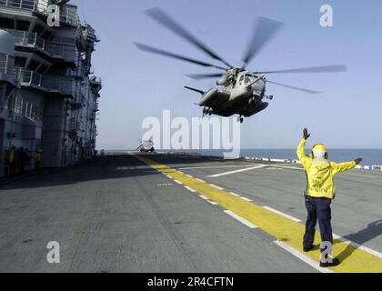 US Navy Aviation Boatswain's Mate Handler 3. Class signalisiert einem MH-53E Super Hallion, dass es frei ist, das Flugdeck des Amphibienschiffes USS Saipan zu verlassen. Stockfoto