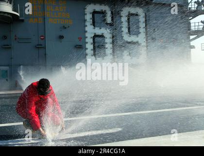 US Navy Aviation Boatswain's Mate (Aircraft Handling) Klasse 3. befreit während eines Tests des Gegenmaßnahmen-Spülsystems an Bord eines Flugzeugs der Nimitz-Klasse einen Sprinkler auf dem Cockpit. Stockfoto