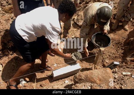 US Navy der Gesundheitskoordinator von Baie St. Anne Hospital, und Baumeister 2. Klasse legte Mörtel für den ersten Stein während einer bahnbrechenden Zeremonie für eine neue Baie St. Anne Hospital Mo. Stockfoto