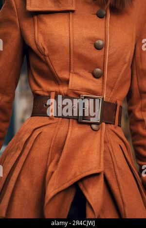 Modische Details der Herbstjacke in leuchtendem Orange mit braunem Ledergürtel. Stilvolles Bekleidungskonzept. Stockfoto