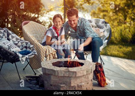 Der Moment der reinen Verbindung und der Liebe zwischen einem Vater und seiner Tochter. Sie teilten die Erfahrung, wie Marshmallows geröstet wurden, wird zum Symbol des Schatz Stockfoto