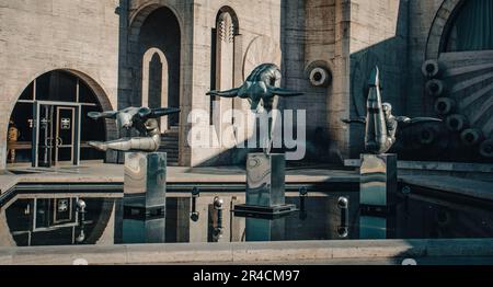 Moderne Kunst - Edelstahlskulpturen von drei Athleten im Pool-Konzeptfoto. Stockfoto