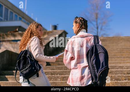 Highschool-Mädchen diskutieren ein Schulfach, während sie nach oben gehen Stockfoto