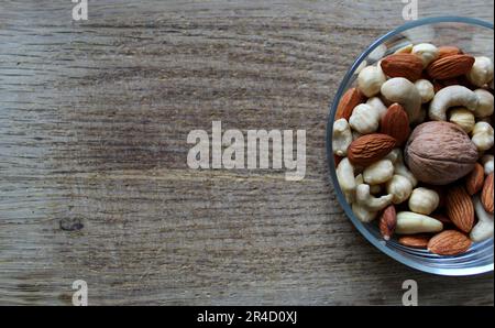 Schüssel mit geschälten Mandeln, Cashew und Haselnüssen und Walnuss auf Einem Holzbrett an der Seite von Image Stockfoto