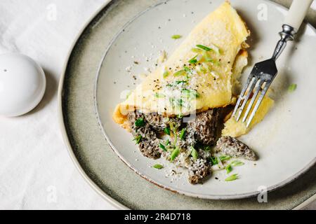 Omelette mit Morchelpilzen in einer cremigen Knoblauchsoße. Stockfoto