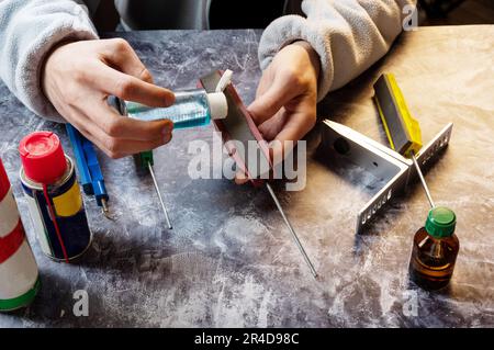 Öl und Schleifstein. Öl auf den Schleifstein gießen. Ich bereite das Schärfen eines Messers vor. Winkelansicht. Stockfoto