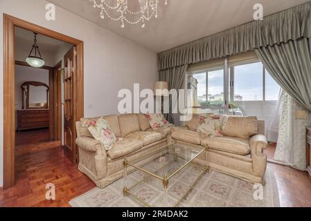 Cremefarbene Stoffsofas mit Teppich und Erkerfenster mit Fenstern und Vorhängen Stockfoto