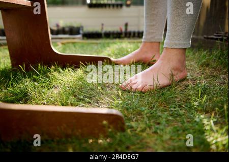 Nahaufnahmen einer Frau, die barfuß draußen auf grünem Gras steht. Verbunden mit der Natur. Gesunder Lebensstil auf dem Land Stockfoto